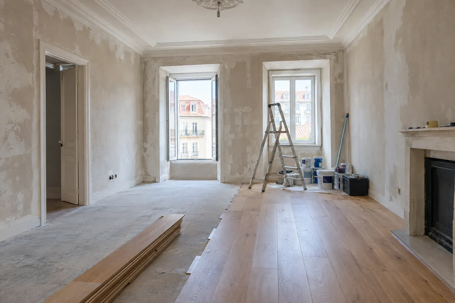 Sala de uma casa portuguesa em remodelação, com paredes por acabar e luz do dia.